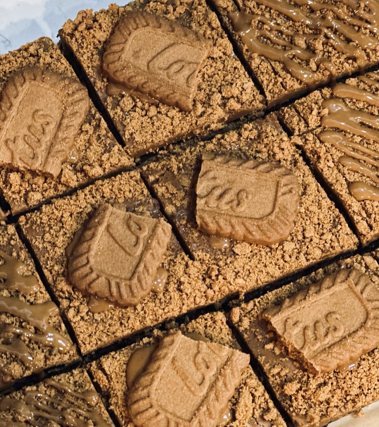 Biscoff cheesecake squares topped with Lotus cookies and caramel drizzle